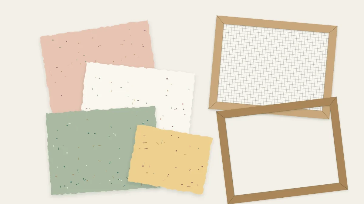 Sheets of handmade paper with soft deckle edges beside a wooden mould and deckle