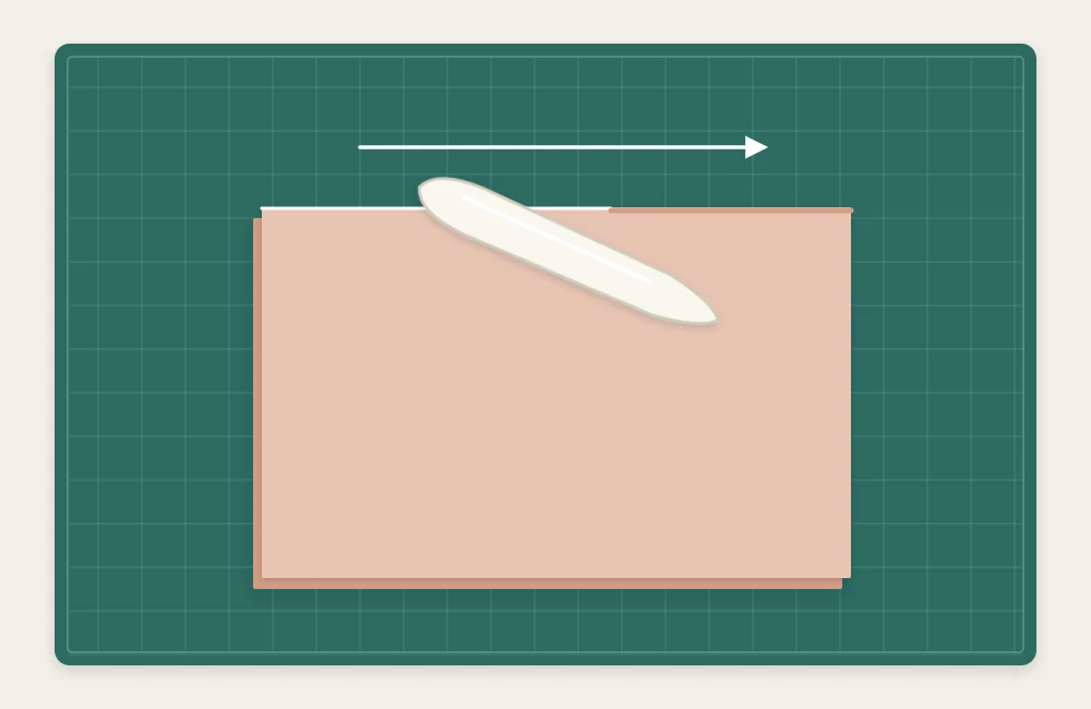 A bone folder being drawn along the folded edge of a card to press it flat